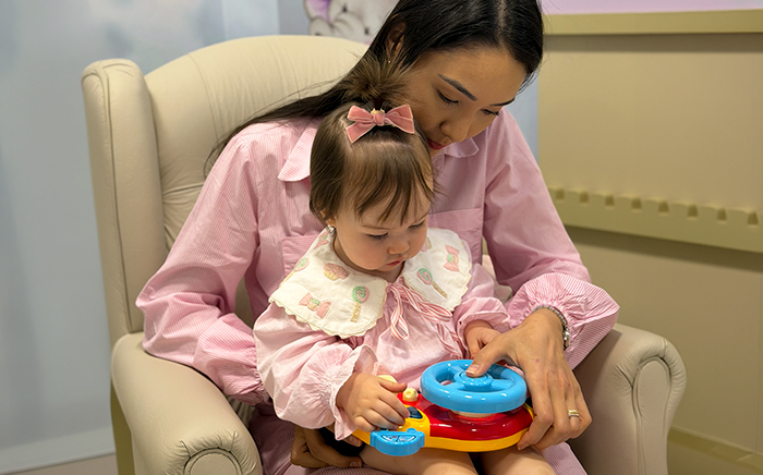 Bebê no colo da mãe brincando durante o atendimento na Maievah